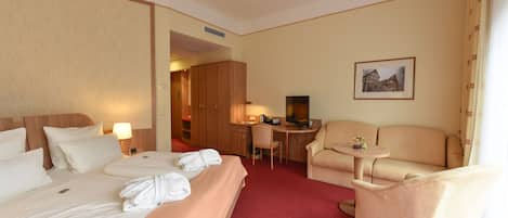 Quarto de hotel com uma cama grande, uma escrivaninha, uma cadeira e um sofá.