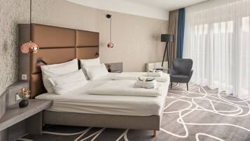 Ein modernes Hotelzimmer mit einem großen Bett, einer Sitzecke, einer Lampe und Blick ins Freie.