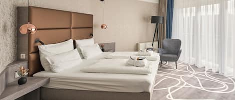 A modern hotel room with a large bed, a seating area, a lamp, and a view of the outdoors.