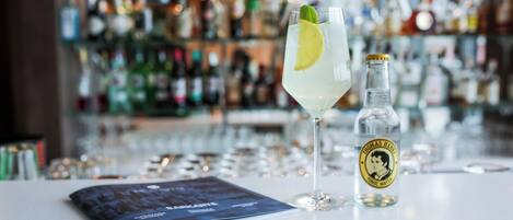 A bar setting with a glass of a clear beverage, a bottle of Thomas Hine Iodic Water, and a menu on the counter.