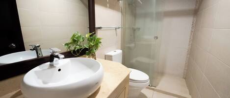 A bathroom with a white sink, a toilet, and a glass shower enclosure.