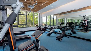 Uma academia moderna com diversos equipamentos de exercício, amplas janelas e piso revestido de carpete azul.