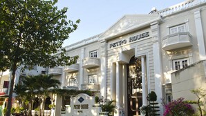 Um edifício grande e branco com uma placa que diz 'PETRO HOUSE HOTEL'.