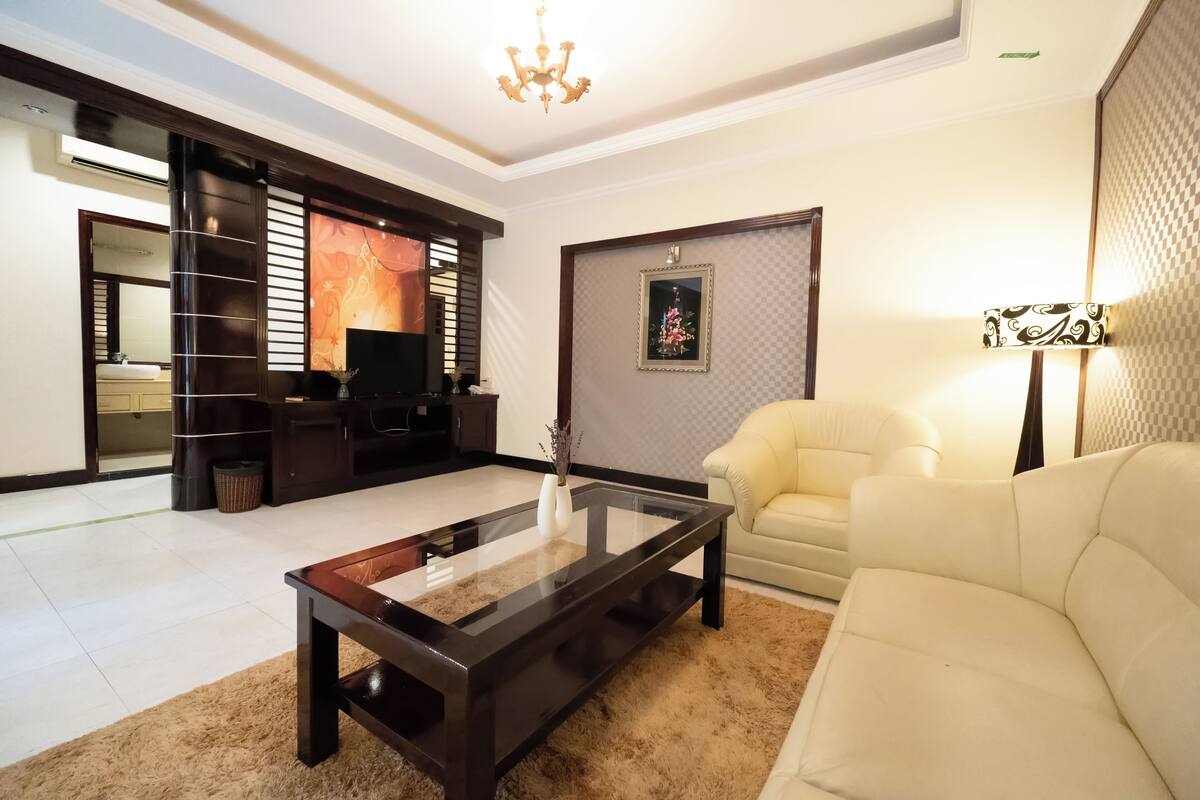 A modern living room with a glass coffee table, a sofa, and a TV.