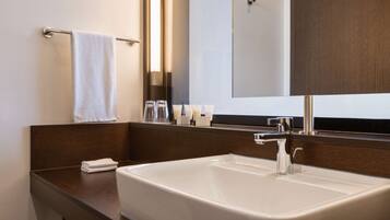 Un baño moderno con un lavamanos grande blanco, un espejo y un perchero para toallas.