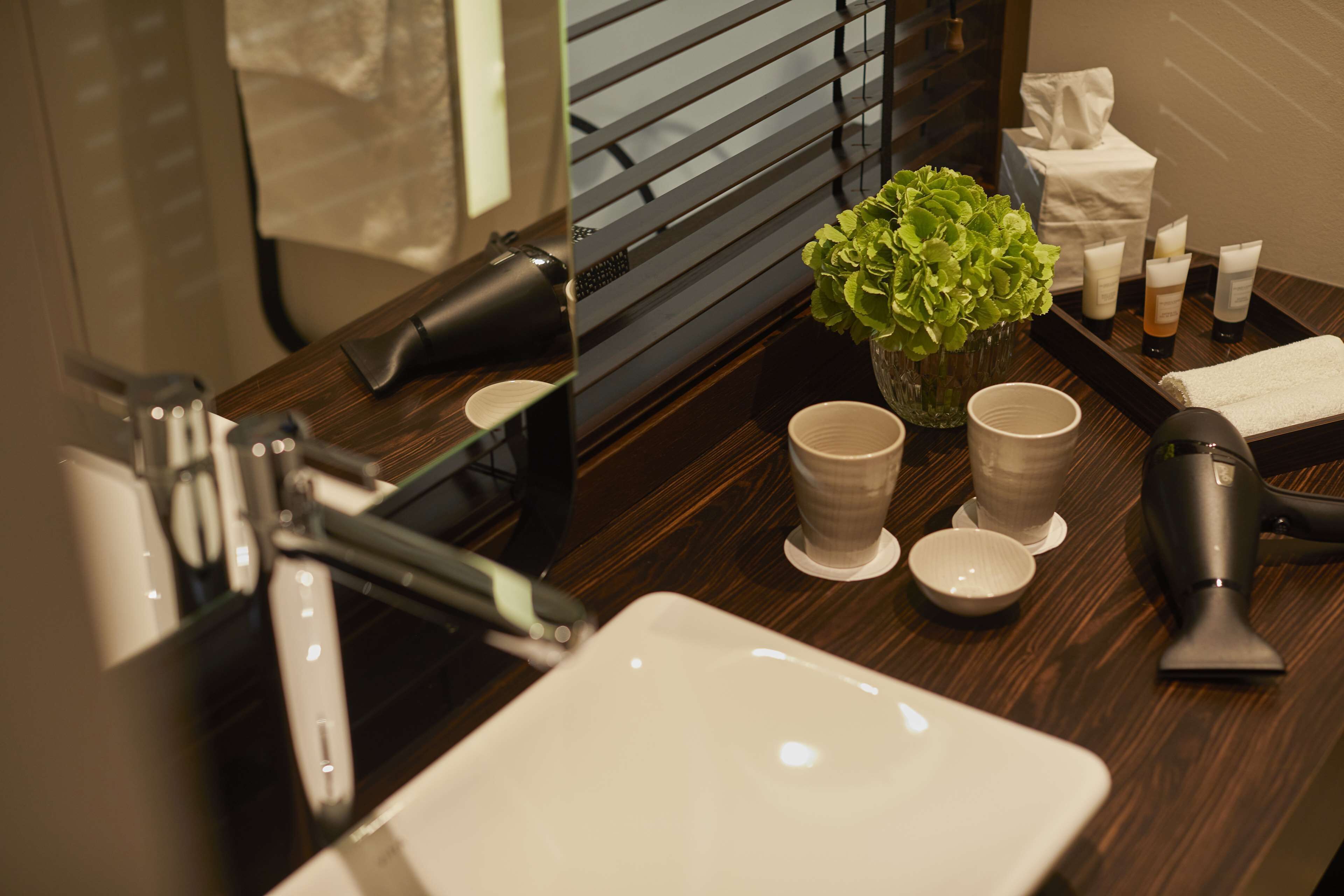 Un meuble-lavabo pour la salle de bain, avec un miroir, un évier et des articles de toilette.