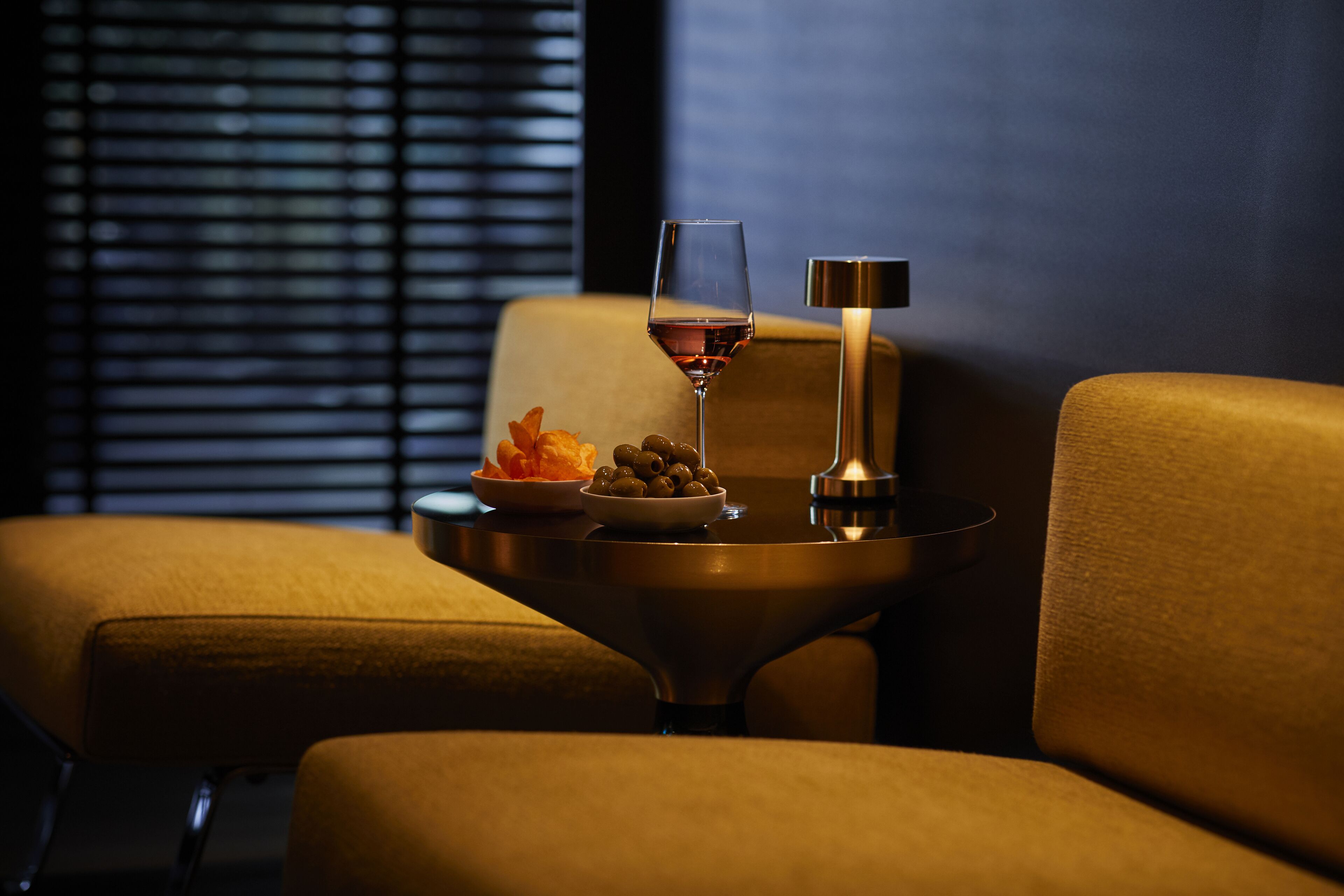 Ein gemütlicher Sitzbereich mit Tisch, Wein Glas, Oliven und Obstschale.
