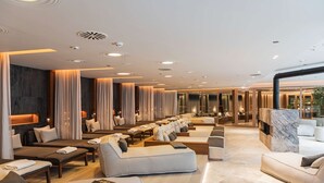 A spacious hotel lobby with multiple seating areas, including sofas and benches, and a marble fireplace.