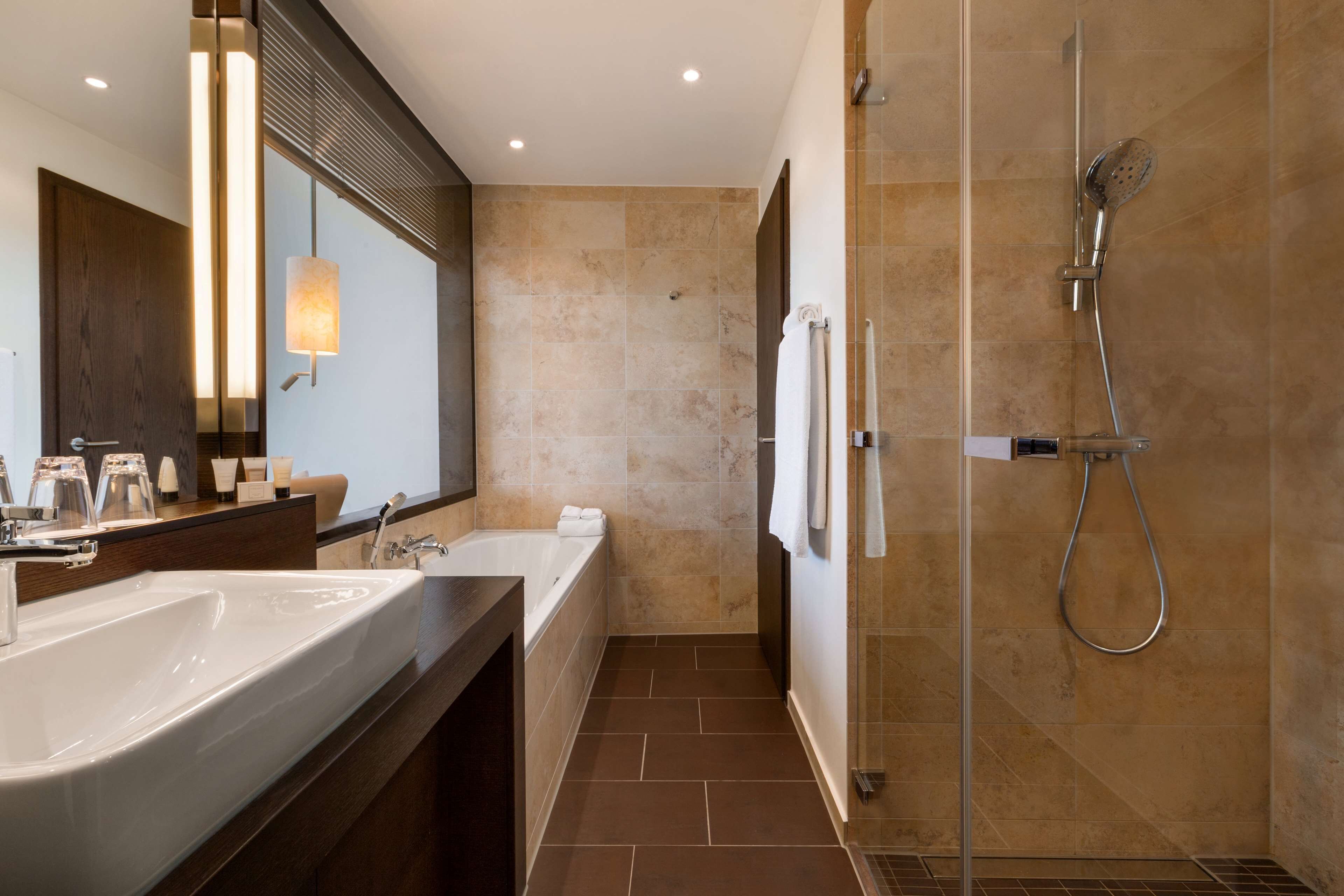A modern bathroom with a large sink, a bathtub, and a glass-enclosed shower.