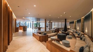 A spacious lobby with a curved seating area, wooden accents, and a large plant.