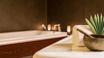 Ein Badezimmer mit einer Badewanne, einem Handtuch, einer Schüssel und einer Pflanze.