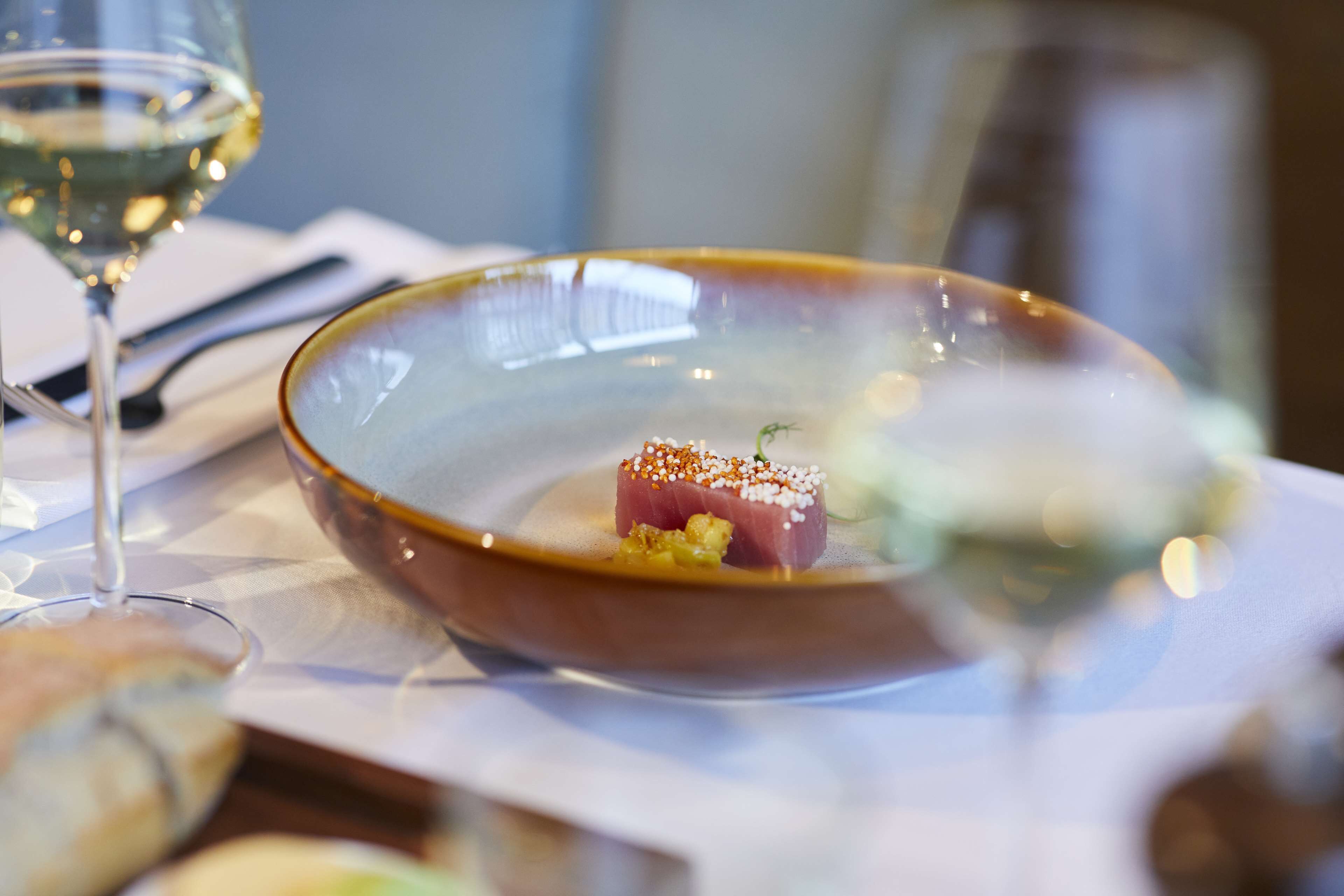 Ein Esstisch mit einem Teller Essen, einem Glas Weißwein und einem Glas Wasser.