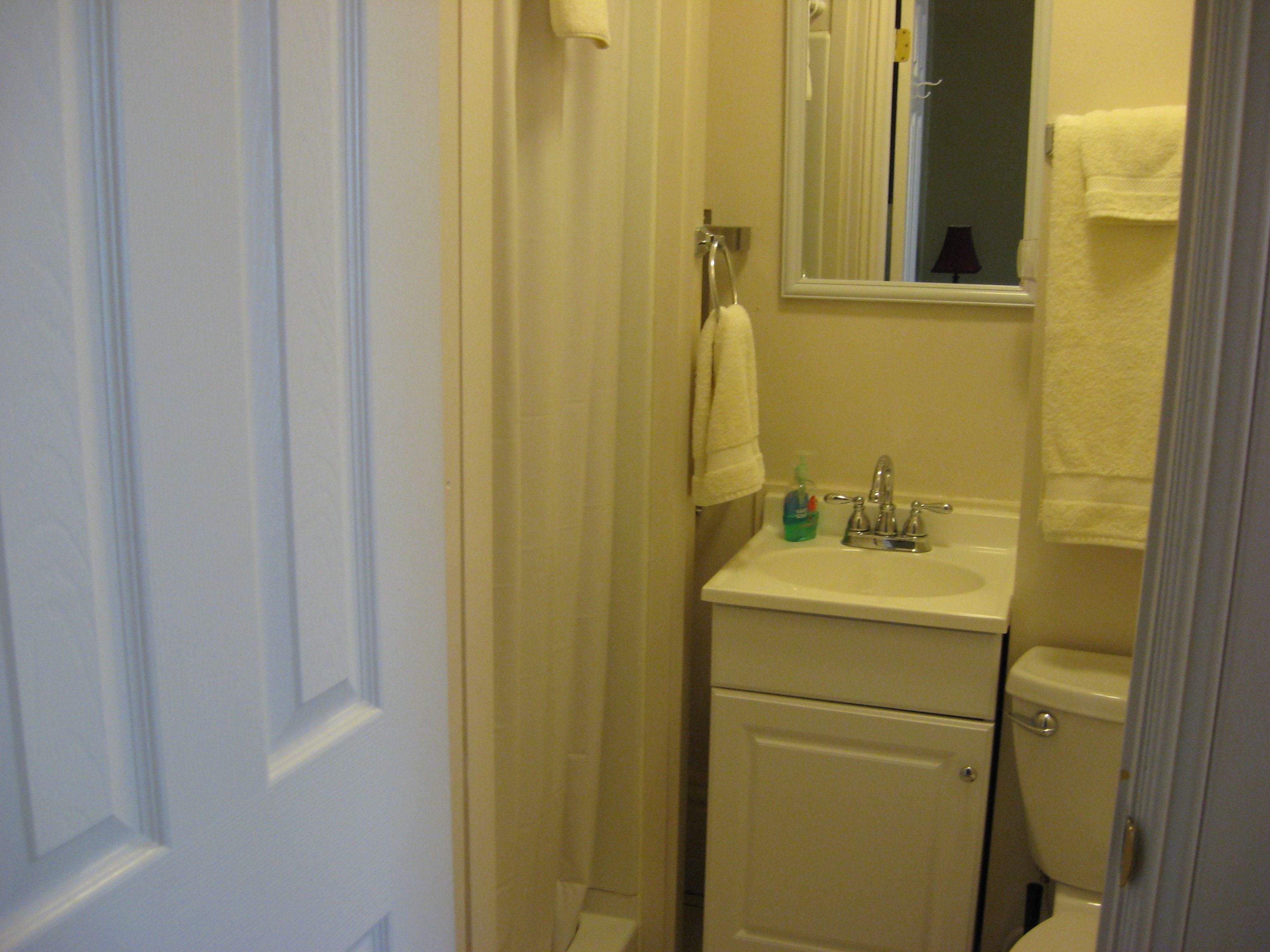 Une petite salle de bain avec des toilettes, un lavabo et un miroir au-dessus du lavabo.
