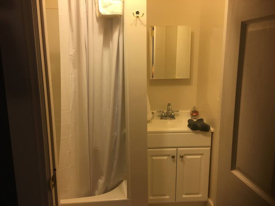 A bathroom with a shower curtain, a sink with a mirror above it, and a cabinet below.