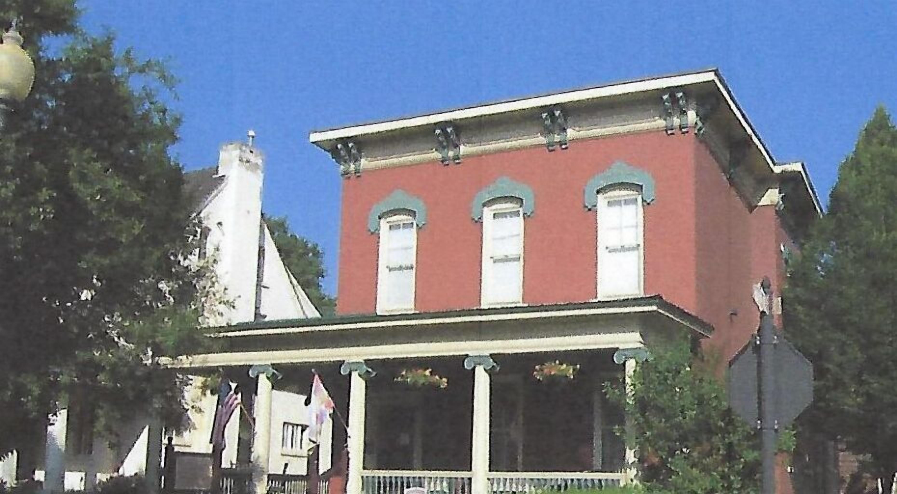 A two-story building with a red facade, white trim, and a central entrance with columns.