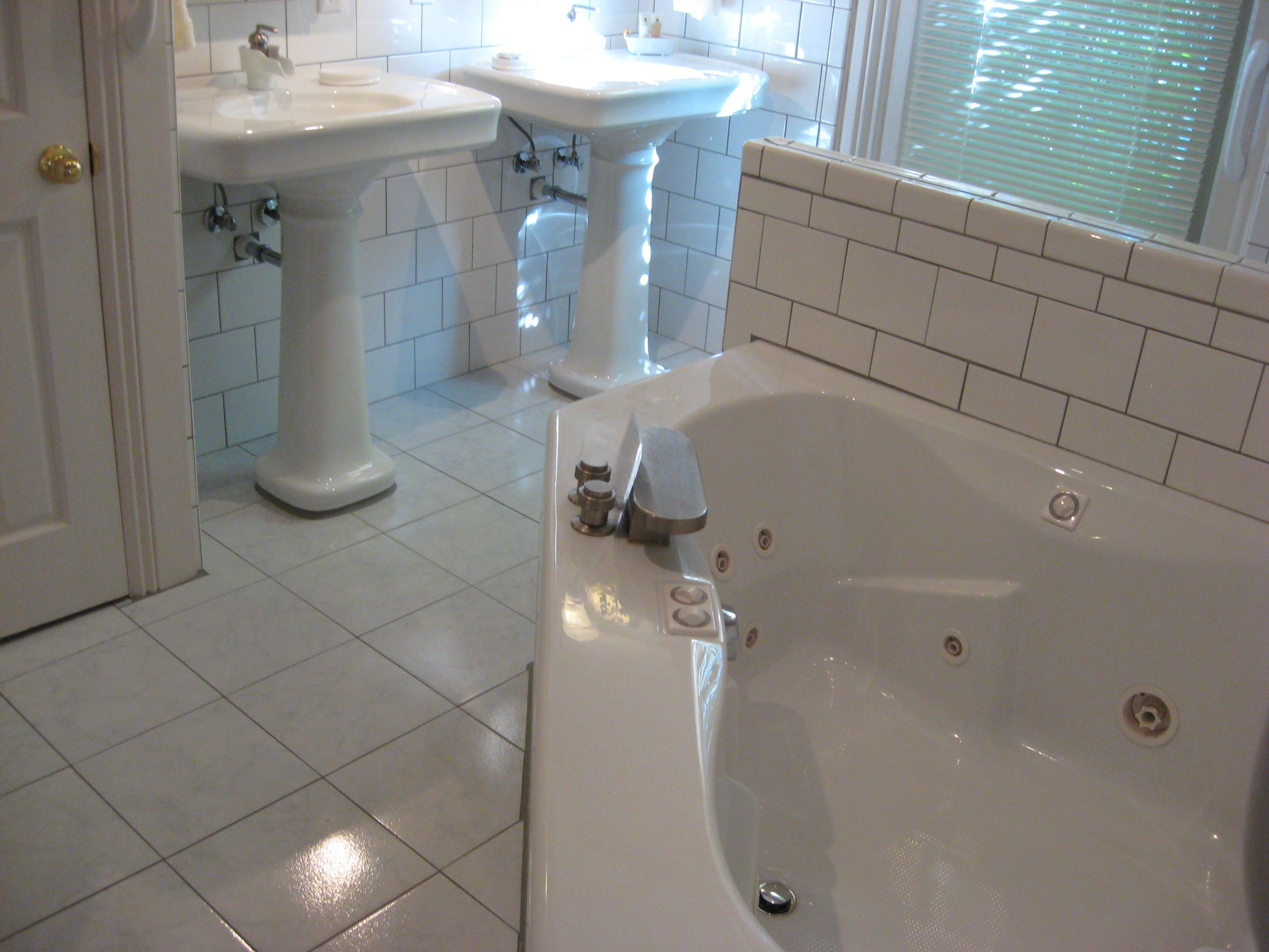 A bathroom with a bathtub, two sinks, and tiled flooring.