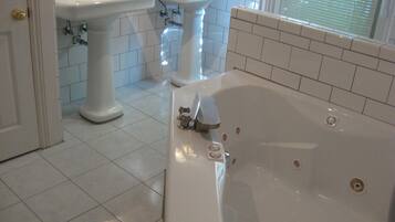 A bathroom with a bathtub, two sinks, and tiled flooring.