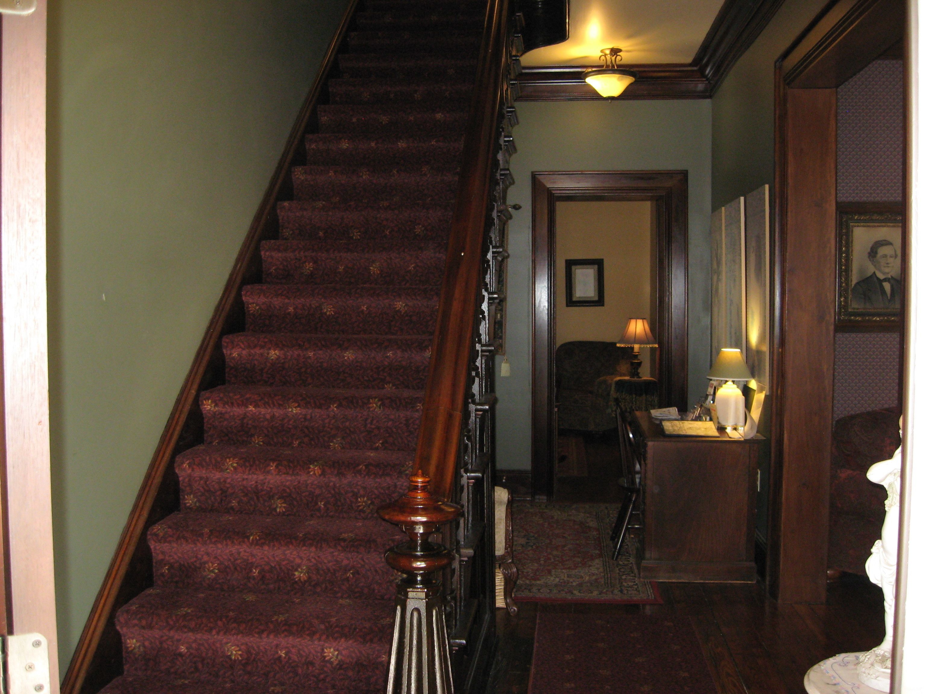 Un escalier avec une rampe en bois et des marches recouvertes de moquette.