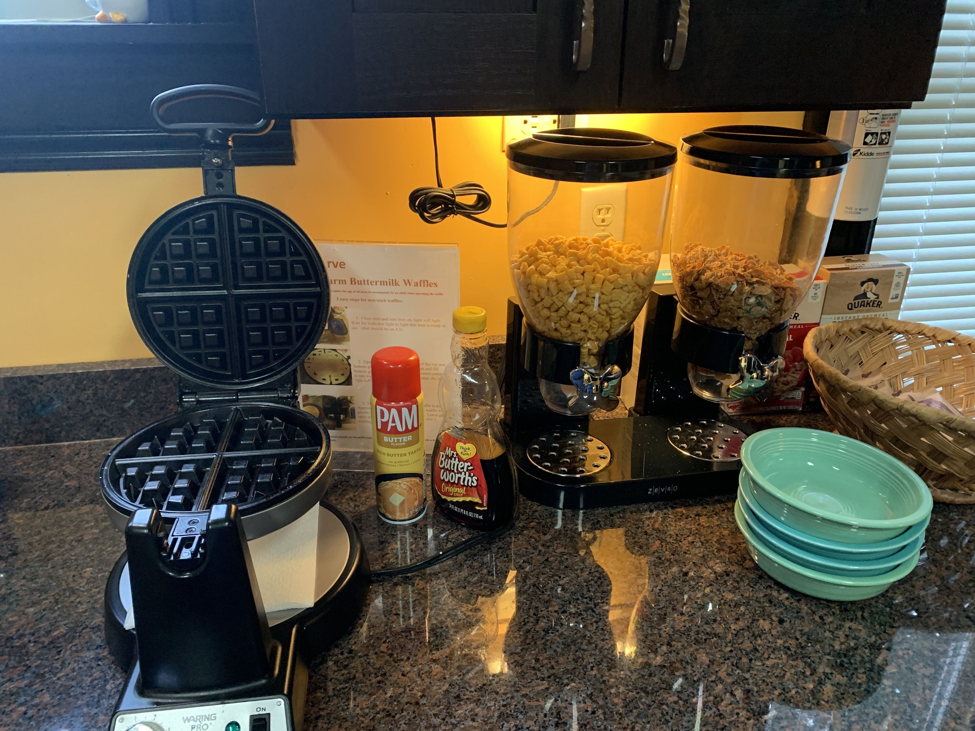 Una cocina con una máquina para gofres, una cafetera y diferentes condimentos en la encimera.