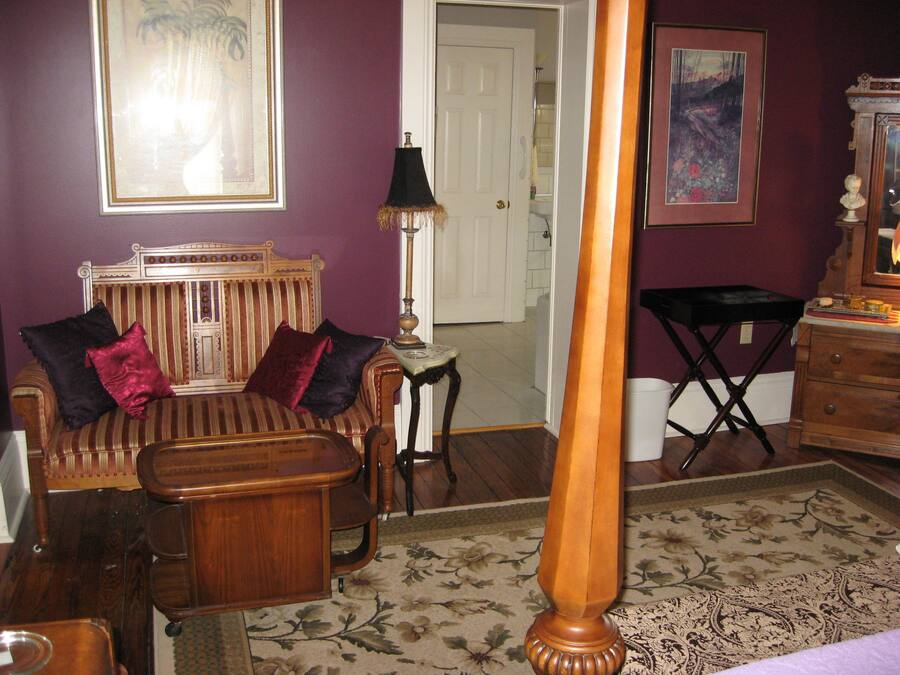 A room with a wooden bed, a striped sofa, a small table, and a lamp.