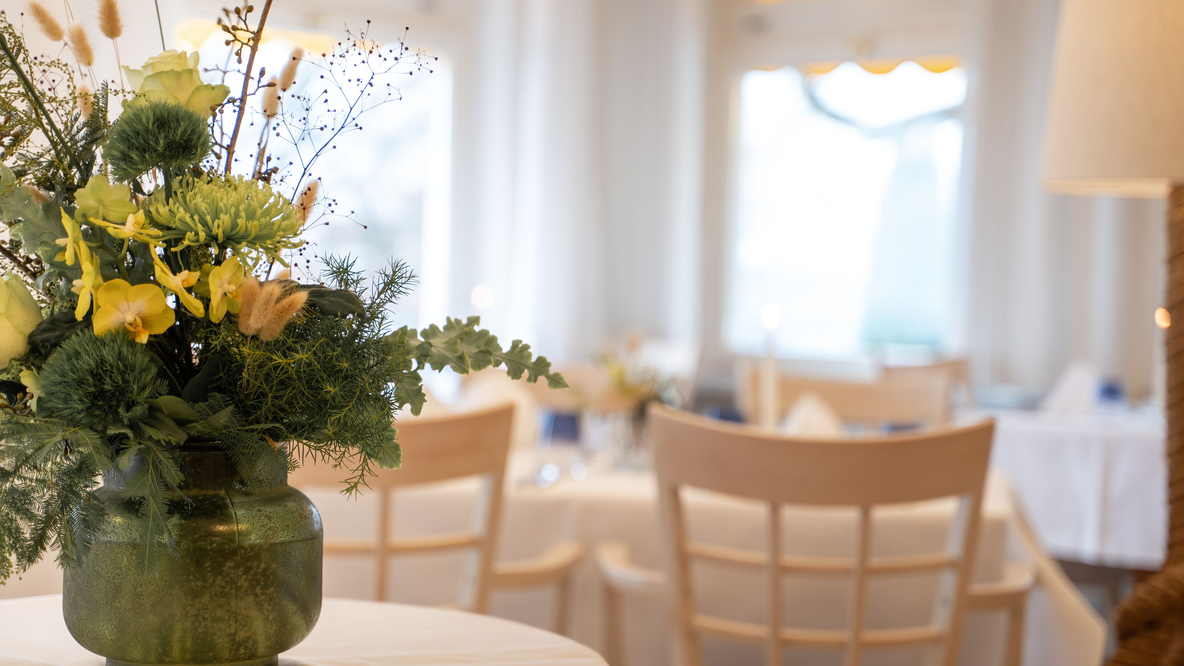 Une table à manger agrémentée d’un centre de table floral, entourée de chaises dans une pièce bien éclairée.