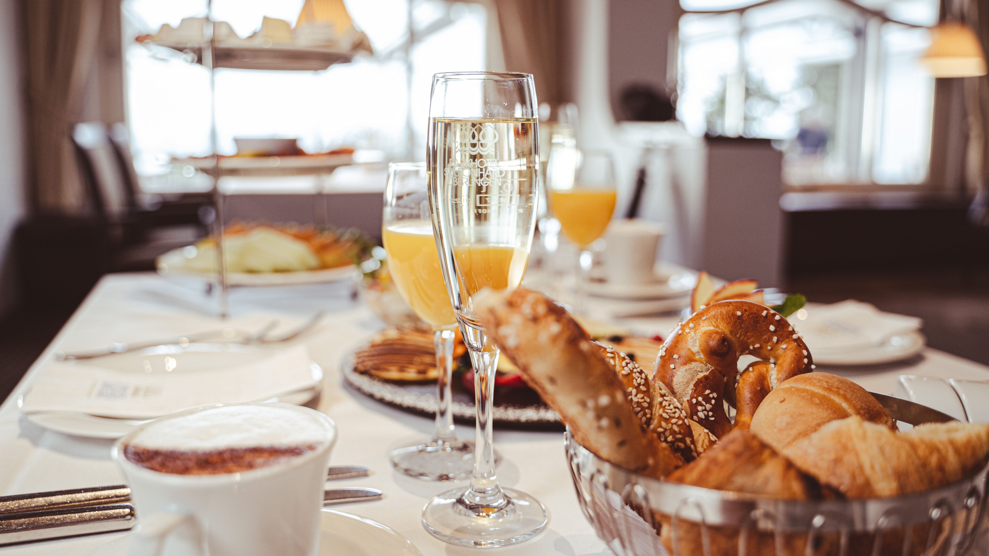 A breakfast setting with croissants, orange juice, and coffee cups on a table.