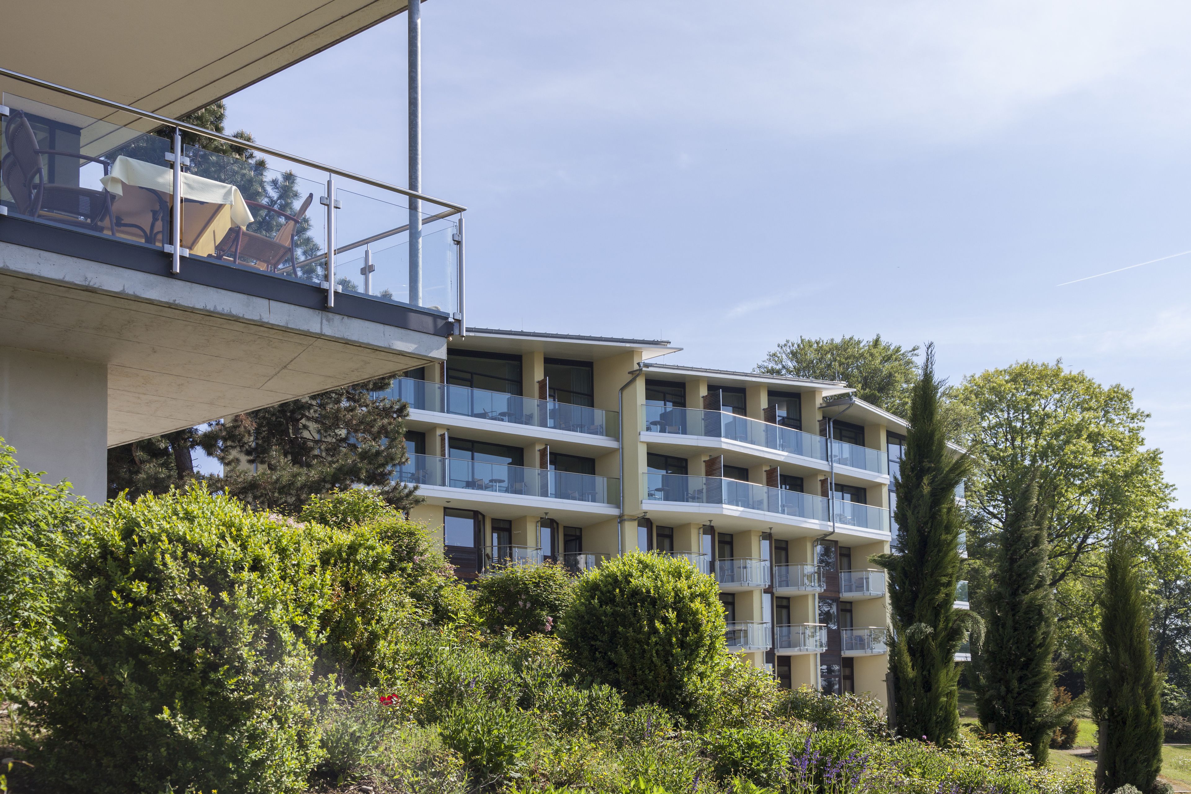 A multi-story residential building with balconies, surrounded by greenery and trees.