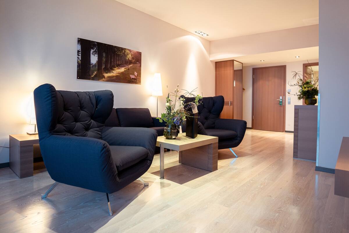 A modern living room with two dark sofas, a coffee table, and a painting on the wall.