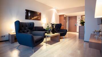A modern living room with two dark sofas, a coffee table, and a painting on the wall.