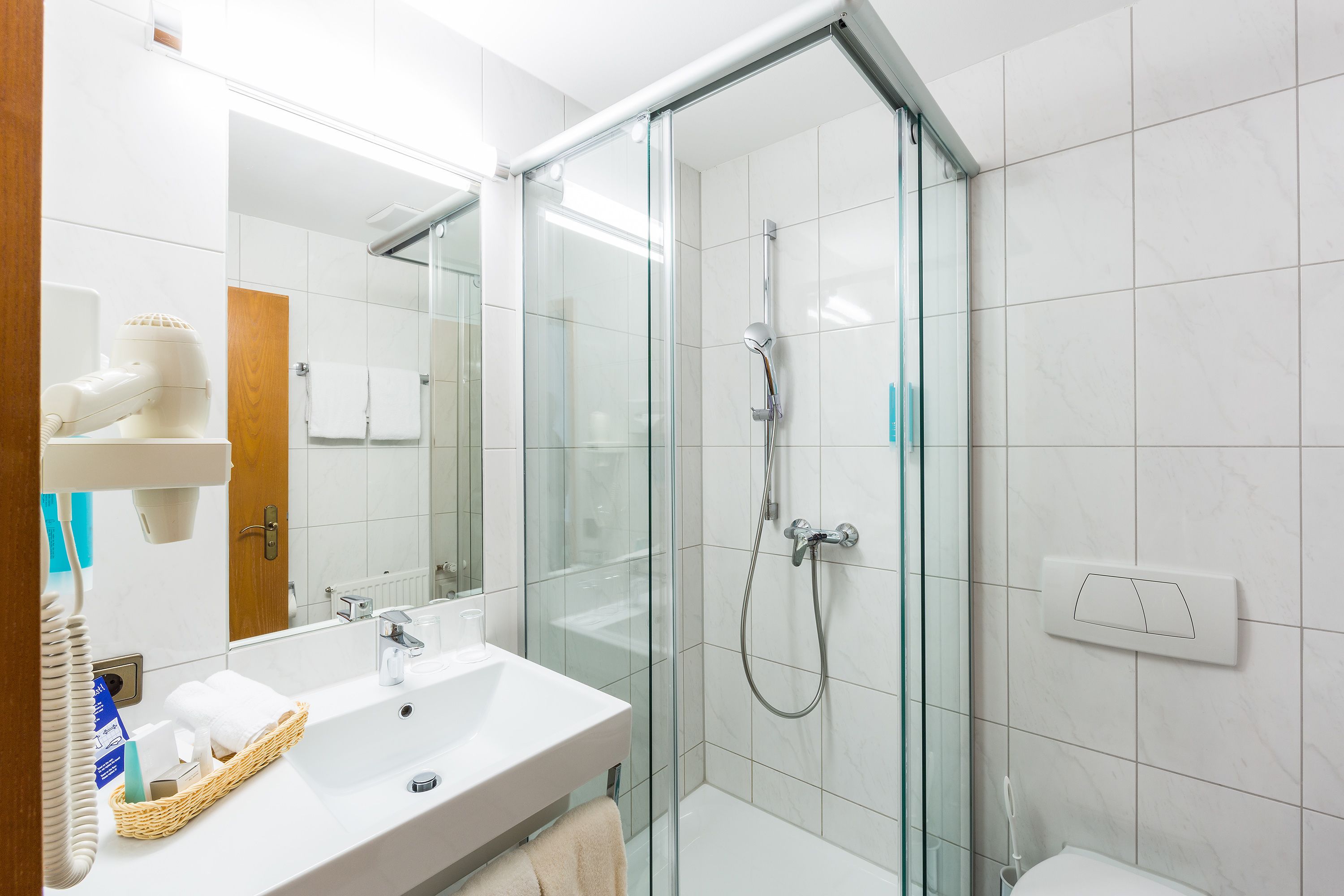 A modern bathroom with a glass-enclosed shower, a white sink, and a mirror.