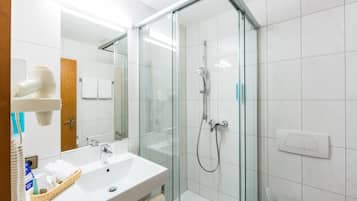 A modern bathroom with a glass-enclosed shower, a white sink, and a mirror.