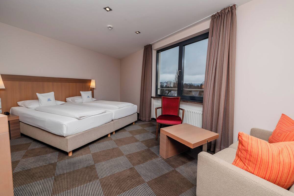 A hotel room with a bed, a desk, a chair, and a sofa.