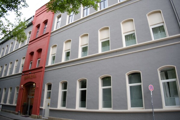 Un edificio de varios pisos con una entrada roja y numerosas ventanas.