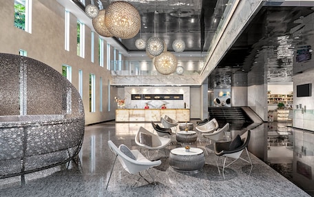 A modern lobby with a reception desk, seating area, and a staircase.