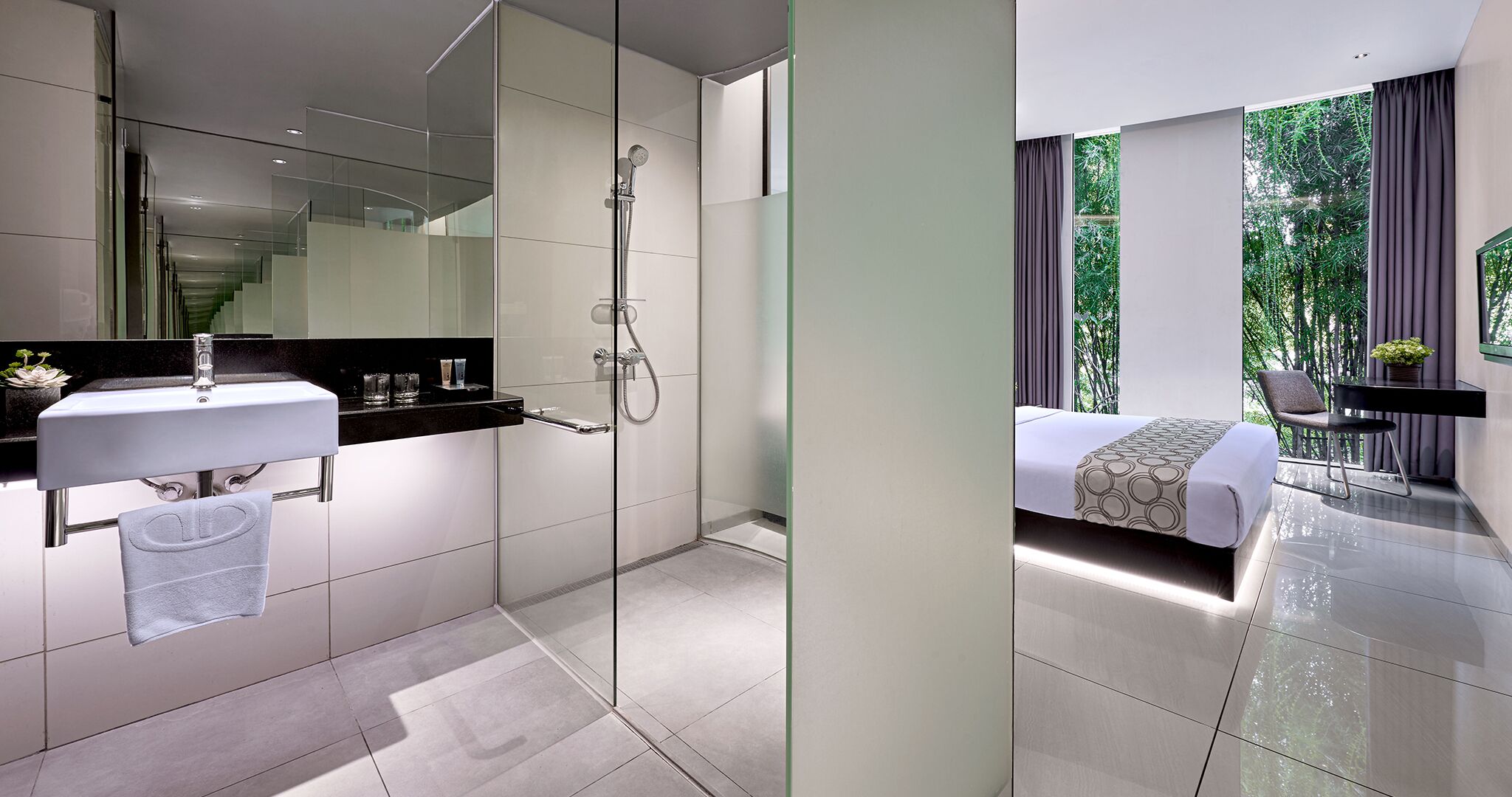 A modern bathroom with a glass shower enclosure, a white sink, and a towel hanging on a rack.