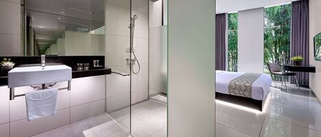 A modern bathroom with a glass shower enclosure, a white sink, and a towel hanging on a rack.