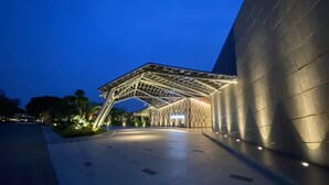 Un edificio moderno con un ingresso caratterizzato da una struttura in metallo originale e una facciata ampia e scura.
