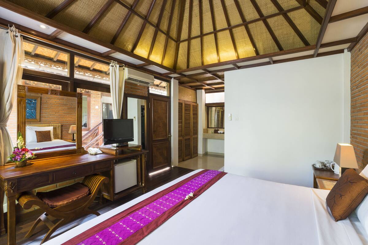 A hotel room with a bed, desk, and a large mirror.