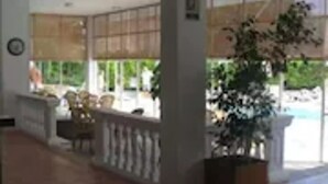 A hotel lobby with a reception desk, seating area, and a large potted plant.