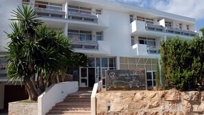 A modern building with multiple balconies, a stone staircase, and a signboard.