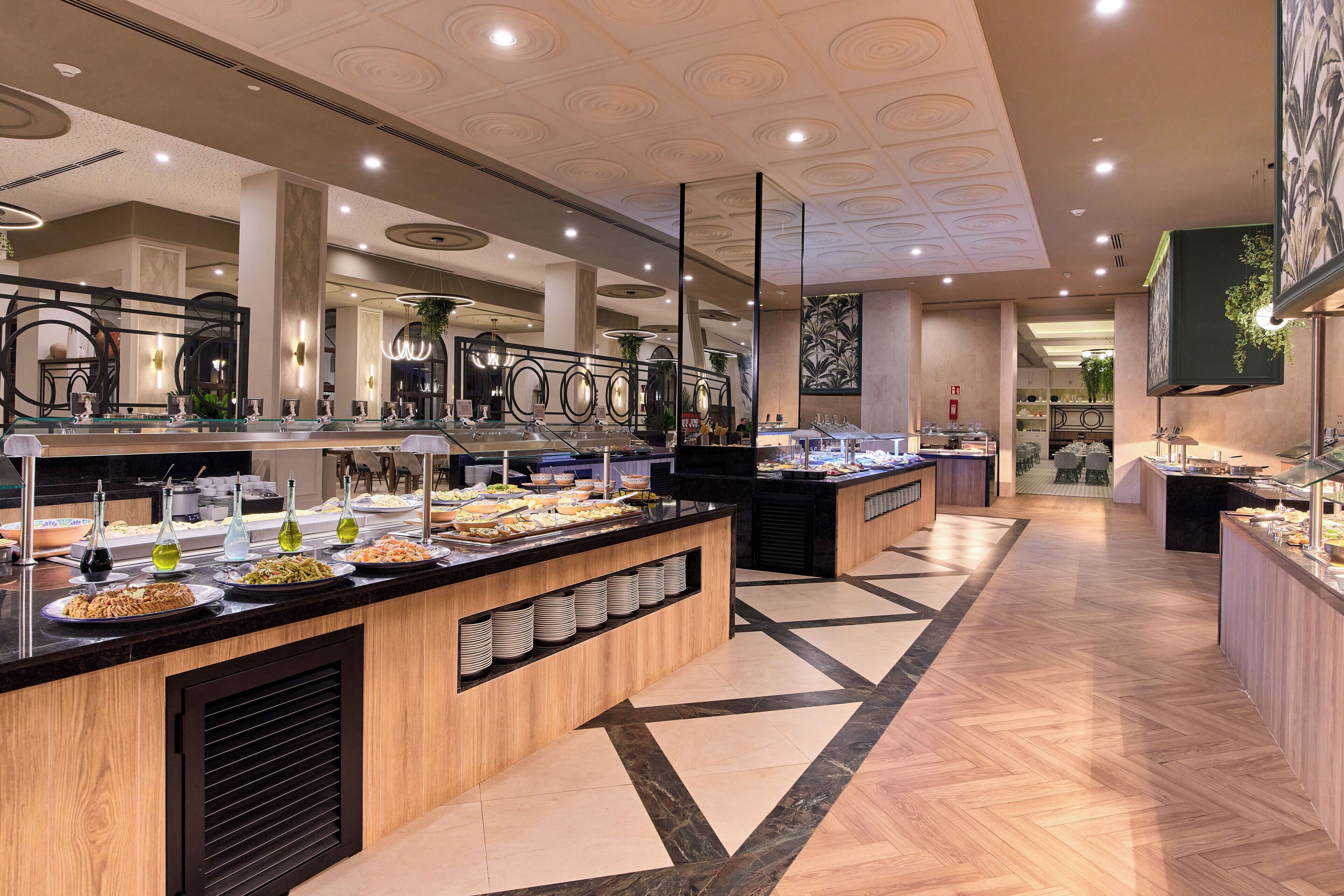A modern buffet area with multiple food stations, a central serving counter, and a patterned floor.