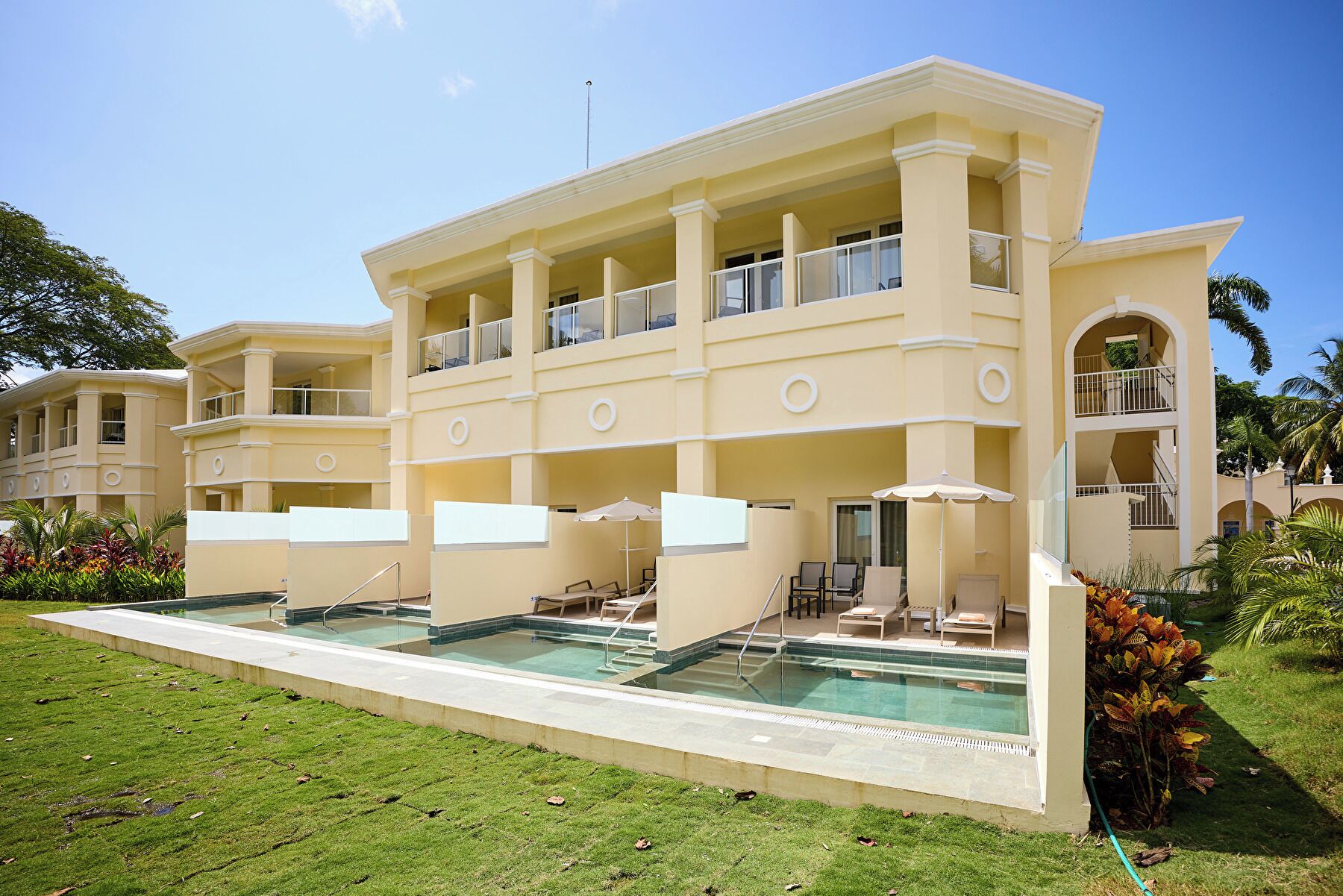 Un hôtel à plusieurs étages doté d’une piscine, d’un espace extérieur aménagé et d’une pelouse bien entretenue.