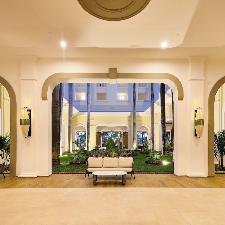 A spacious lobby with a central seating area, large arched doorways, and a view of a lower level with balconies.