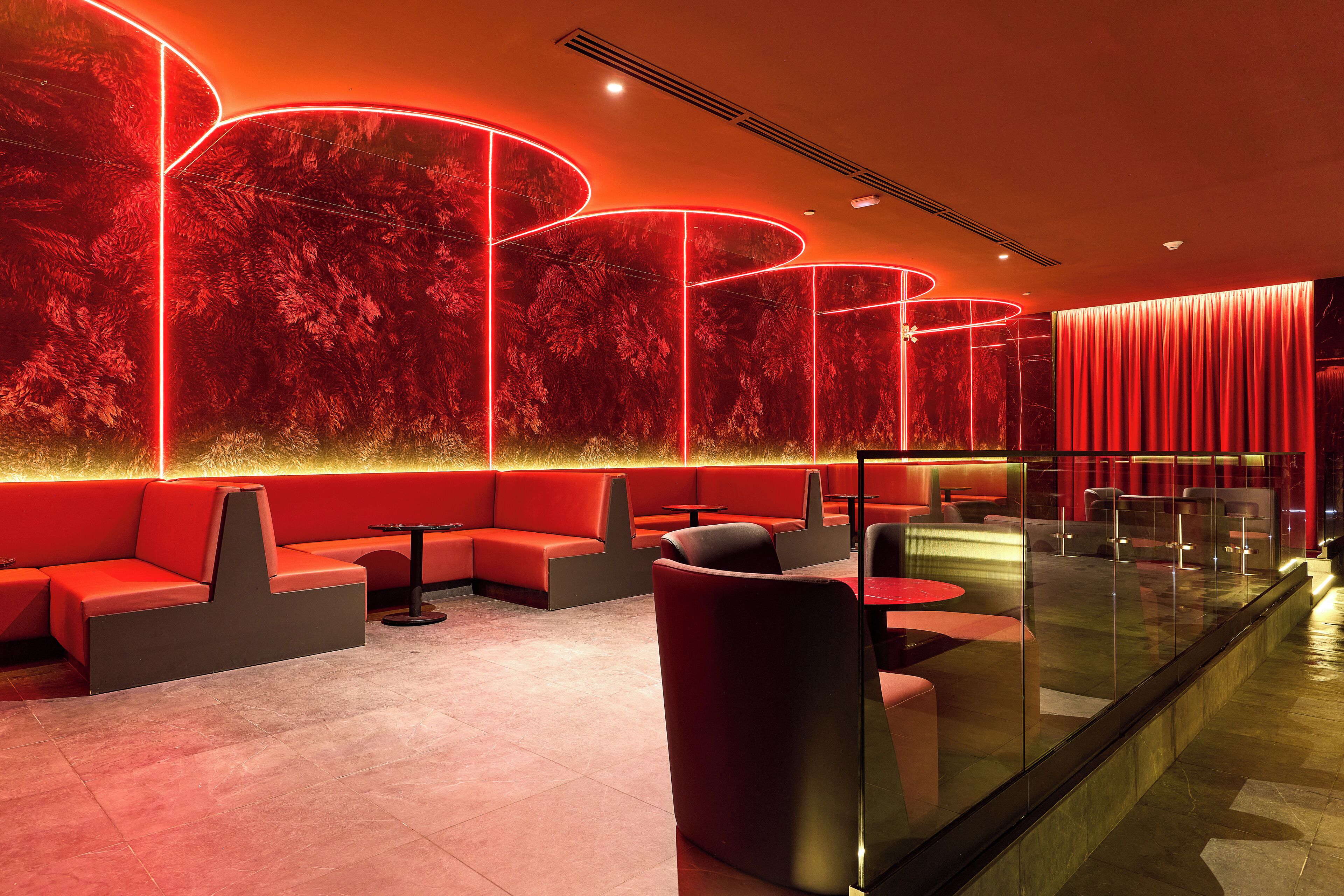 A modern interior with red seating, glass partitions, and ambient lighting.
