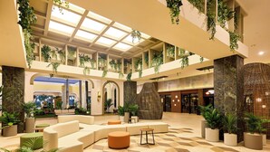 A spacious lobby with a high ceiling, multiple seating areas, and a variety of potted plants. - Hotel Riu Guanacaste - All Inclusive (Sardinal)