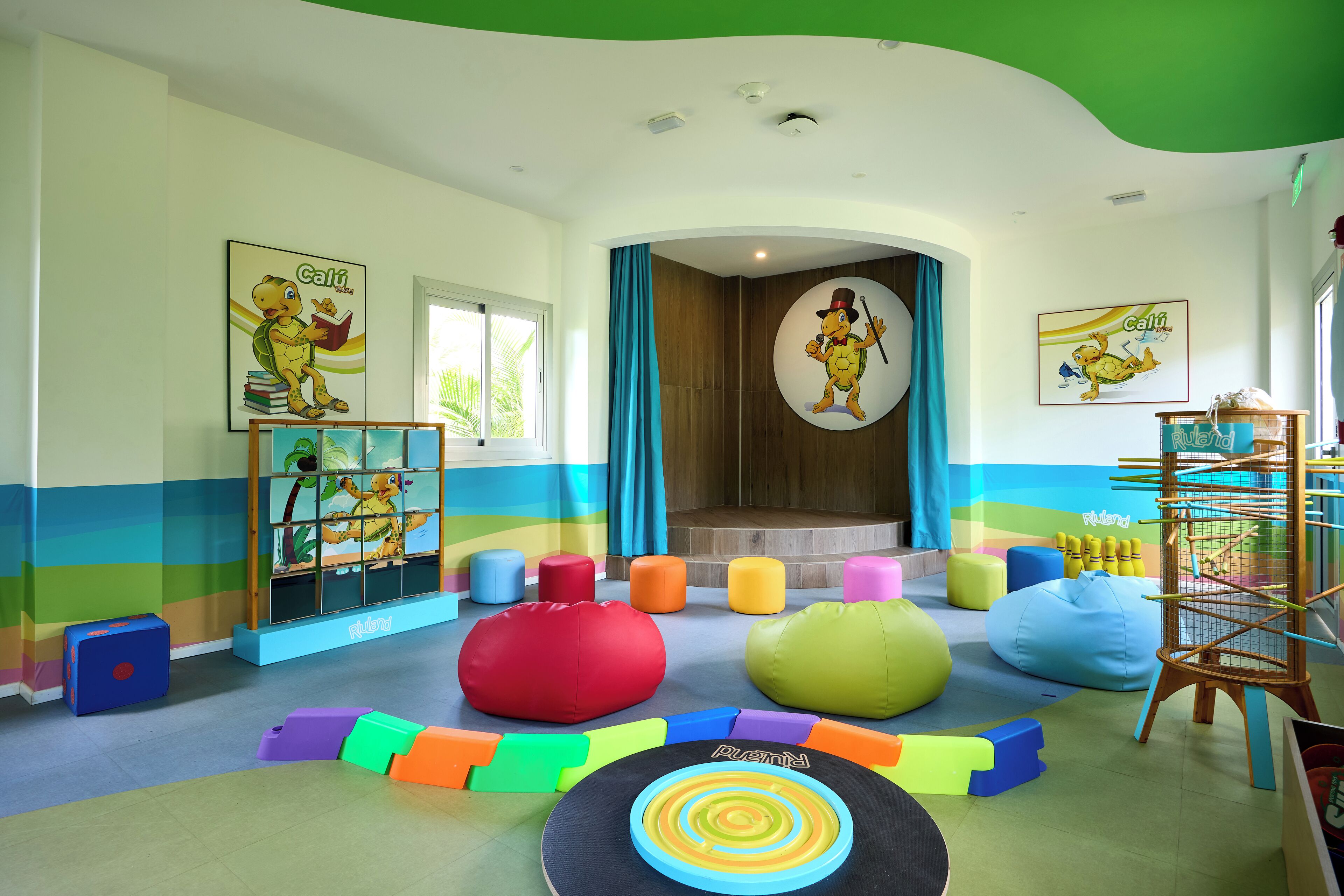 Ein Kinderspielbereich mit bunten Sitzsäcken, einer Spielmatte und lehrreichen Postern.