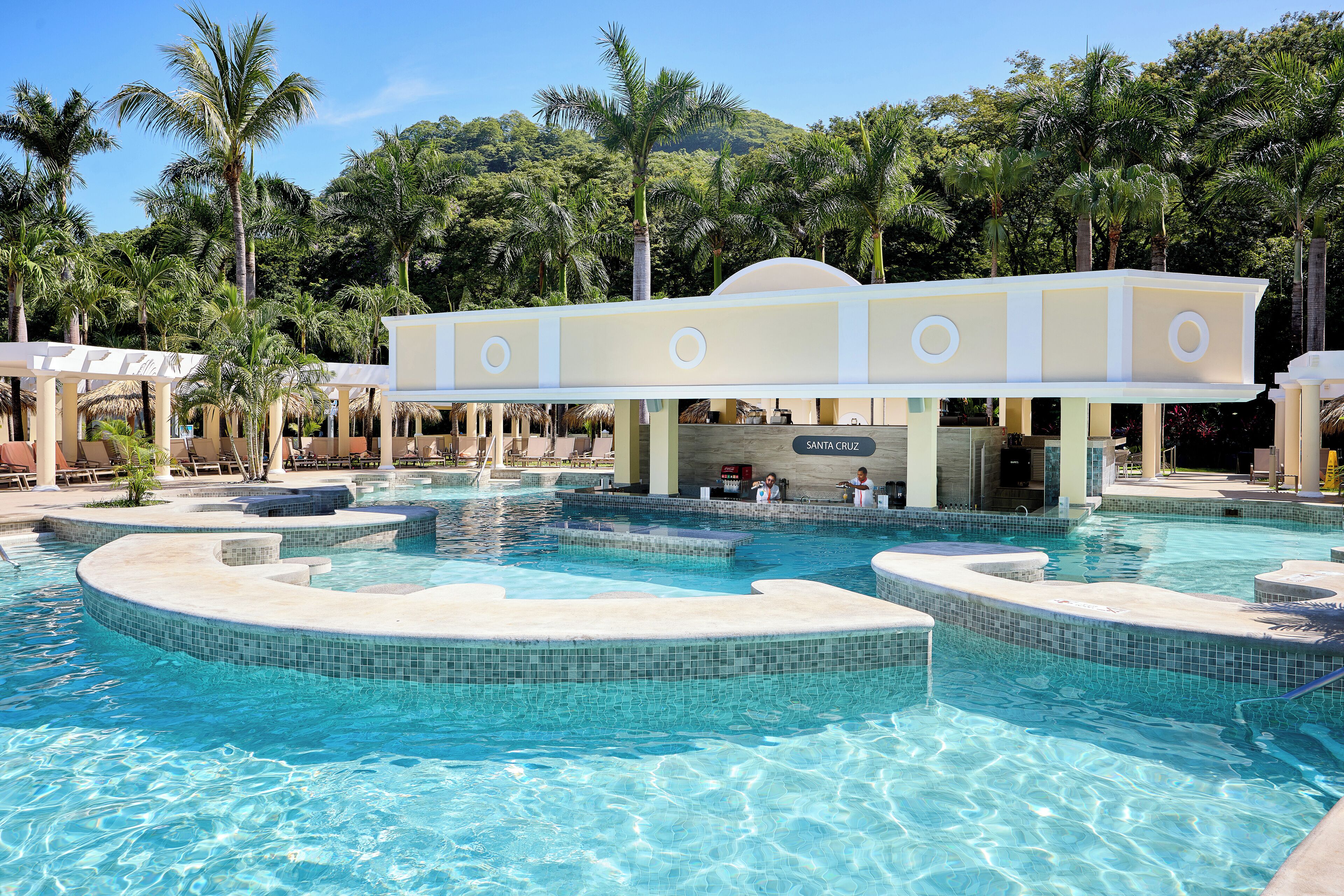 A large outdoor swimming pool with multiple levels and a covered seating area.
