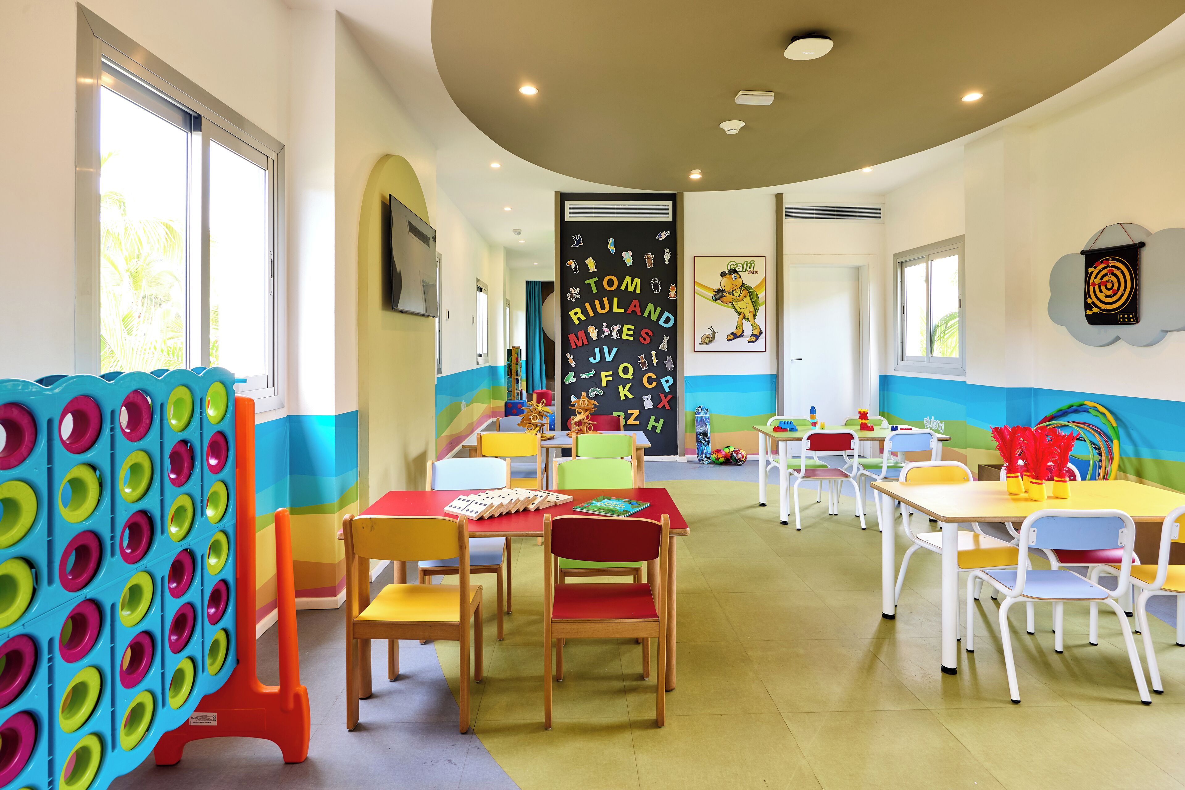 Un aula luminosa con mobiliario colorido y decoración educativa.