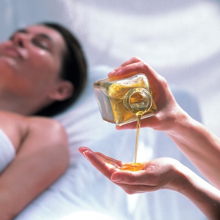 A person lying in bed with a bottle of liquid being poured into their hand.