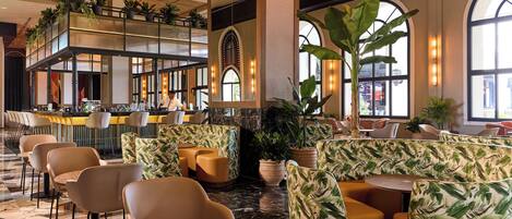 A spacious lobby with a high ceiling, a bar area, and seating arrangements.